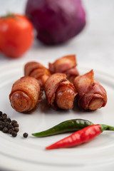 Sausage wrapped pork belly on a white plate.