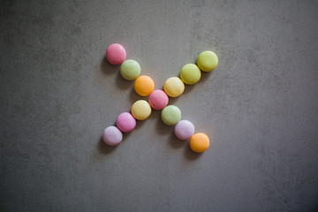 cross from multi-colored candies on a gray table