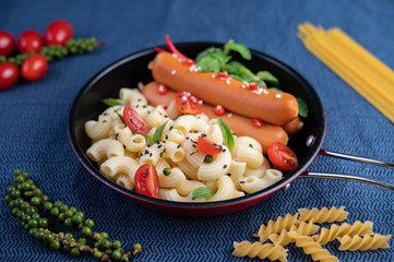 Fried macaroni and sausage in a frying pan.