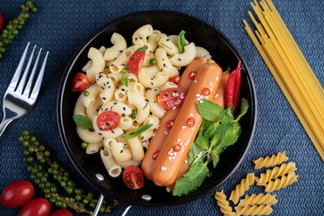 Fried macaroni and sausage in a frying pan.