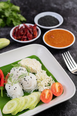 ืRice noodles in a banana leaf with beautifully laid vegetables and side dishes. Thai food.