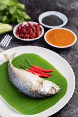 Mackerel placed on banana leaves on a white plate.