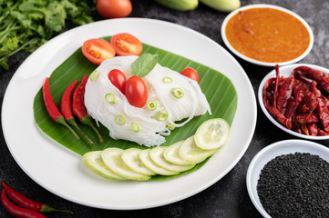 ืRice noodles in a banana leaf with beautifully laid vegetables and side dishes. Thai food.