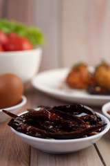 Dried chili fried on a white plate on a wooden floor.