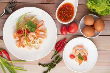 Stir-fried instant noodle with prawn and crab stick along  in a white dish.