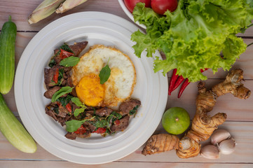 Stir fried basil liver with fried egg in a white plate.
