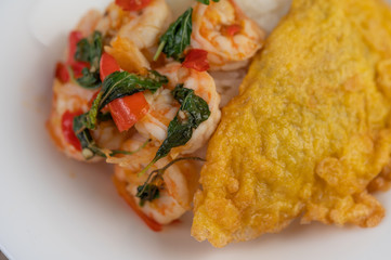 Rice topped with shrimp and omelet on a white plate.