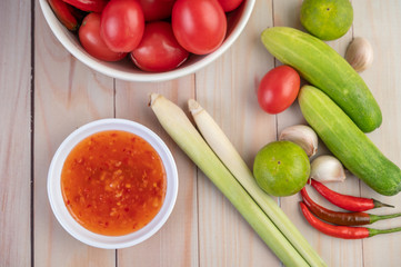 Cucumber, lemon, tomato, garlic, chili with sauce on the wood floor.
