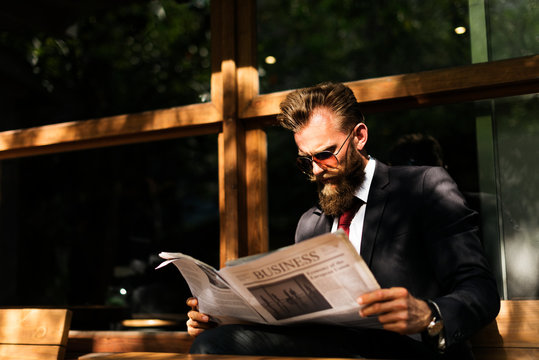 Businessman reading newspaper at coffee shop - Powered by Adobe