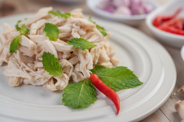 The chicken that is bordered is cooked and placed in a white plate along with mint leaves.