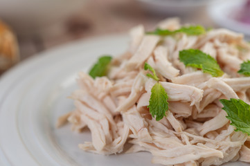 The chicken that is bordered is cooked and placed in a white plate along with mint leaves.