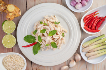 The chicken that is bordered is cooked and placed in a white plate along with mint leaves.