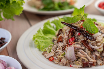 Deep-fried mackerel topped with galangal, pepper, mint, red onion in a white dish.