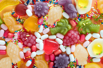 Flatlay of assorted jelly fruits and sprinkles textured background