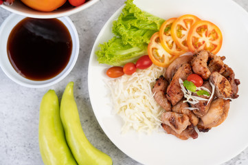 Grilled pork cutlet with tomatoes and salad, arranged in a white dish.