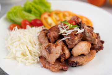 Grilled pork cutlet with tomatoes and salad, arranged in a white dish.