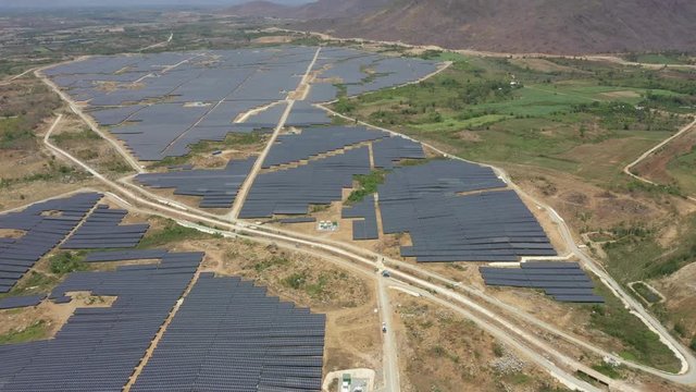 Solar panel produces green, environmentaly friendly energy from the setting sun. View from drone. Landscape picture of a solar plant that is located inside a valley, Ninh Son, Ninh Thuan, Vietnam