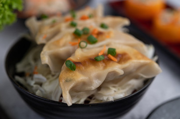 Gyoza in a black cup with Sushi.