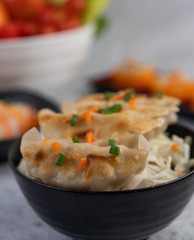 Gyoza in a black cup with Sushi.