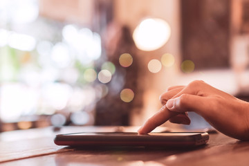 Womanhand using smartphone to do work business, social network, communication in public cafe work space.