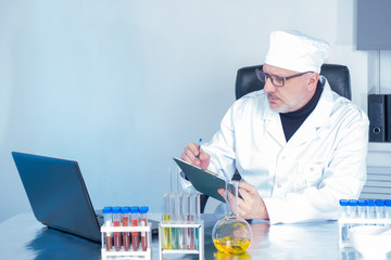 Medical concept. The doctor makes notes on the tablet against the background of laboratory dishes. Medical test. Confirmation of the diagnosis is based on tests. Monitoring the course of treatment.