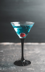 Blue martini cocktail with cherry on the rustic background. Selective focus. Shallow depth of field.