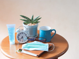 Sansevieria Boncel with alarm clock , blue cup of coffee , notebook,eye glasses, hygienic mask and alcohol hand gel on wooden table.stay safe, self isolation, quarantine concept.