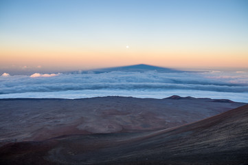 Fototapeta na wymiar Shadow of the Mauna Kea volcano above clouds and near the moon.