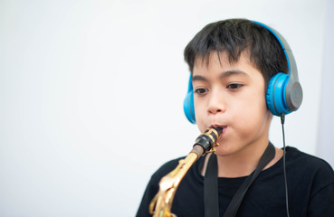 Little Asian boy study saxophone instument music online at home