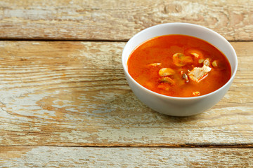 Dish with thai tom yam soup on a wooden table.