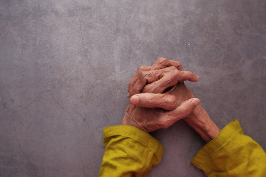 Hands of an old woman folded one over the other.