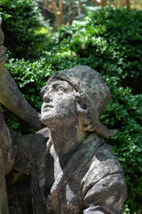 Garden statue of a boy looking up, sunlit face, vertical aspect