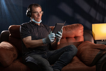 Middle aged man working at home on his computer for the coronavirus using protective equipment such as gloves and mask