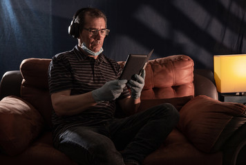 Middle aged man working at home on his computer for the coronavirus using protective equipment such as gloves and mask