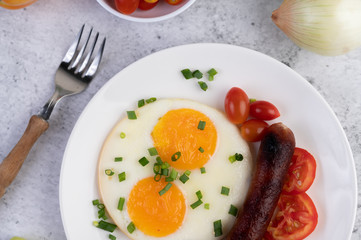 Breakfast consisting of bread, fried eggs, tomatoes, Chinese sausage and mushrooms.