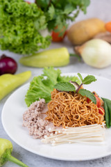 Stir-fried noodles with minced pork, edamame, tomatoes and mushrooms in a white plate.