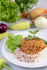 Stir-fried noodles with minced pork, edamame, tomatoes and mushrooms in a white plate.