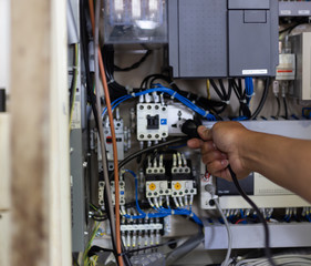 Technician setting  electric control box of machine in factory 
