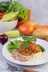 Stir-fried noodles with minced pork, edamame, tomatoes and mushrooms in a white plate.