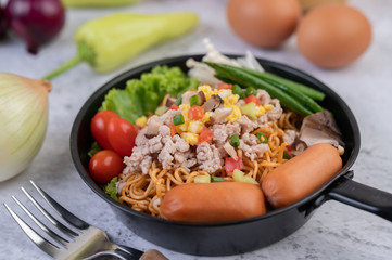 Stir-fried noodles with minced pork, edamame, tomatoes and mushrooms in a pan.