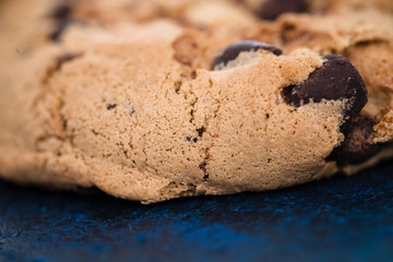 Detail of handmade chocolate chip cookie on dark blue background