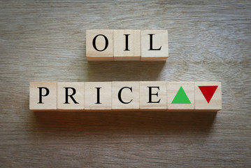 Top view of wooden block written with alphabet of Oil price with green and red arrow represent the...