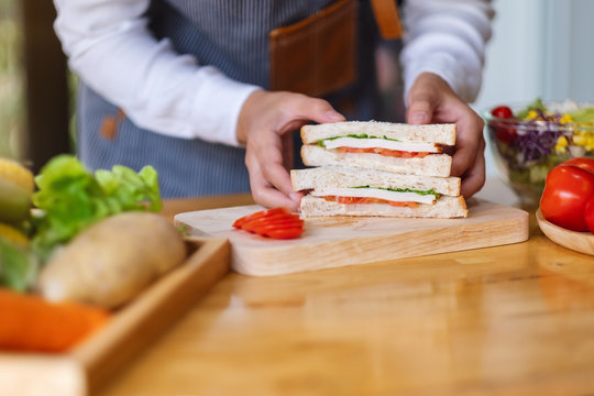 Closeup image of a female chef cooking and holding a piece of whole wheat sandwich in kitchen