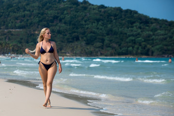 beautiful blonde on vacation walks along the beach