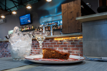 A piece of cake, a glass of wine and a pail of ice on a blurred background 