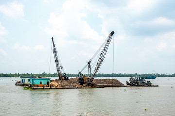 Fototapeta premium Exploiting sands on the Mekong River. Boats carrying sand on the river in Vinh Long, Vietnam.