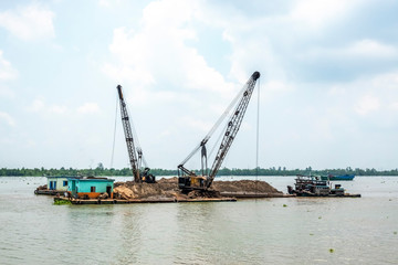 Fototapeta na wymiar Exploiting sands on the Mekong River. Boats carrying sand on the river in Vinh Long, Vietnam.