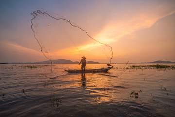 Picture of Asian fishermen on a wooden boat Thai fishermen catch fresh water fish in the natural river, traditional Thai fishermen at the morning sun on the lake of Thailand