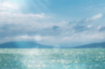 Fototapeta premium Blurred summer natural marine tropical blue background and sunbeams of light. Sea and sky with white clouds. Copy space, summer vacation concept