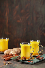 Golden Cinnamon  Turmeric Milk. Trendy hot Healthy drink with turmeric roots and spices. Indian Masala Haldi Doodh. Wooden background